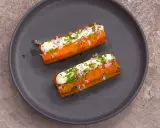 Två gyllene, rektangulära tater tots toppas med gräddfil, finhackad rödlök och gräslök.