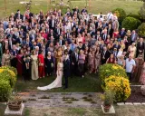 Una gran familia celebra una boda íntima al aire libre. Todos posan sonrientes para la foto grupal en un jardín verde.
