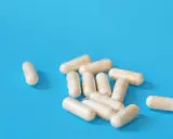 Kapsułki na niebieskim tle. Mogą symbolizować skutki uboczne leków na prostatę, które wpływają na codzienne życie.