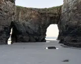 Felsbögen am Praia das Catedrais, die wie Kathedralen wirken, mit Sand und Meer im Hintergrund.