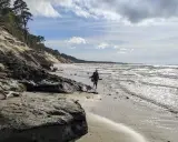 Spacerująca osoba na plaży w Ustce, w oddali widać orzechowo-brązowe klify.