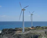 Zwei Windräder an einer felsigen Küste Spaniens, die saubere Energie erzeugen.