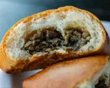 Puszysta bułka z pieczarkami, przekrojona na pół, odsłaniająca aromatyczne, drobno posiekane grzyby.