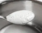 En sked med skummande bikarbonat utan aluminium, redo att användas för rengöring eller bakning.