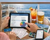 Coppia controlla il bilancio della loro crociera di una settimana su un tablet, con cocktail e birra sul tavolo.