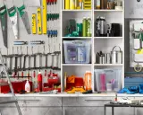 Werkzeugwand mit Sägen, Wasserwaagen, Schraubendrehern und Zangen. Regale mit Behältern und Flaschen. Ein perfektes Ideen Garage Ordnungssystem.