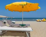 Lettini e ombrelloni gialli sui bagni Rimini, con pedalò gialli pronti per il mare azzurro.