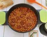Un plato humeante de garbanzos con chorizo, listo para disfrutar con pan crujiente.