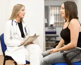 Medico parla con paziente, discutendo di tumori in giovani. Speranza e supporto in un momento difficile.
