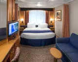 Cabina garantita MSC quando viene assegnata: letto matrimoniale, divano blu, TV e oblò rotondo.