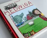 Okładka książki "Hedwiga" Fridy Nilsson, idealna dla 7 latka. Zabawna ilustracja z dziewczynką, owcą, kotami i autobusem.
