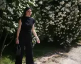 Kobieta w czarnym kombinezonie, obok kwitnących krzewów. Chcesz wiedzieć, co zrobić, żeby czarne ubrania nie obłaziły?
