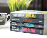 Kolejność czytania książek Magdy Stachuli: "Oszukana", "W pułapce", "Trzecia", "Idealna". Obok filiżanka.