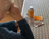 Starsza osoba z rękami na głowie, obok leki. Zastanawia się, renta wdowia komu przysługuje.