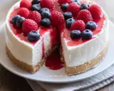 Cheesecake con mascarpone, guarnita con lamponi e mirtilli freschi, con una colata di salsa rossa.
