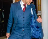 A man in a blue checkered suit, white shirt, and red tie. He's showing off the paisley lining of his jacket, and the bottom button on his vest is unbuttoned.