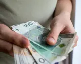 Dłonie liczą banknoty 100 zł. To może być pomoc de minimis dla przedsiębiorcy.