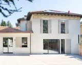 L'abbinamento colori facciata e serramenti crea un'armonia moderna. La casa bianca con dettagli decorativi si fonde con le persiane e gli infissi grigio chiaro.