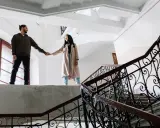 Pareja tomados de la mano en una escalera, ¿qué es ser posesivo? Él la mira, ella sonríe.
