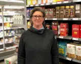 Kvinna i mataffär, redo för en matresa i Sverige. Hyllorna är fyllda med kaffe, havregryn och andra svenska matvaror.