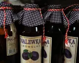 Butelki nalewki lwóweckiej z etykietami i ozdobnymi sznurkami.