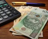 Kalkulator, długopis i polskie banknoty, w tym 100 zł. Przygotowanie do rozliczenia karty podatkowej.