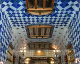Interno della Casa Batlló: soffitto ondulato con piastrelle blu e bianche a rombi, finestre in legno e luci soffuse.