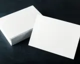 Pila de tarjetas blancas sobre fondo oscuro. El gramaje del papel es ideal para impresiones de alta calidad.