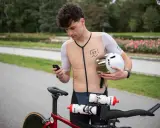 Kolarz sprawdza na telefonie, jaka kadencja na rowerze jest optymalna. Trzyma kask i przygotowuje się do jazdy.