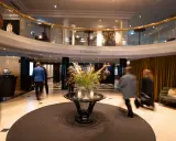 Elegant hotell park lobby med en blomsterdekor i mitten. Människor rör sig förbi i en suddig rörelse.