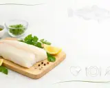 Świeży filet z dorsza na desce z cytryną i ziołami. Niska zawartość dorsz kcal czyni go idealnym wyborem dla dbających o linię.