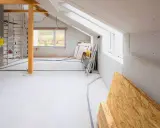 Przebudowa poddasza na pokoje. Widoczna dobudowa do domu w trakcie prac, materiały budowlane, rusztowania i instalacje.