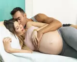 Para, obejmujący ciężarną partnerkę, czule całuje ją w czoło. Czy za pierwszym razem można zajść w ciążę? To pytanie, na które odpowiedź przynosi przyszłość.