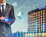 Biznesmen analizuje dane hotelowe na tablecie, widoczne wykresy i budynek hotelu. Skuteczne monitorowanie cen kluczem do sukcesu.