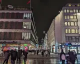 En livlig stockholm shopping street på kvällen. Folk promenerar förbi Åhléns City och Ur & Penn.
