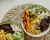 Zwei Schüsseln mit gesunden Reis Rezepten zum Abnehmen: Reis, Bohnen, Mais, Süßkartoffeln, Avocado und Feta.