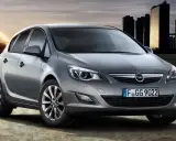 Szary Opel Astra J 1.7 CDTI z nowoczesnymi światłami i felgami, na tle miasta i energetycznego kręgu.