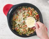 Un delicioso risotto de verduras en una sartén, con queso rallado a punto de ser añadido.