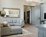 A grey sectional sofa with patterned pillows sits on a rug in a modern living room.