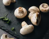 Świeże pieczarki na czarnej desce. Zastanawiasz się, czy pieczarki można mrozić? Tak, można je mrozić, zachowując ich smak i aromat.
