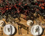 Decoración festiva para una boda en diciembre. Mesa de madera con ramas de pino, bayas rojas y detalles rústicos.