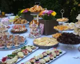 Ein üppiges Brunch Buffet im Freien mit Croissants, Quiche, Brownies, Sandwiches und süßen Leckereien.