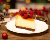 Sernik creme brulee z malinami i miętą, udekorowany na drewnianym stole, w świątecznej scenerii.