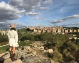 Mujer con sombrero y botas de cowboy admira las murallas de Ávila, un lugar perfecto para visitar con niños.