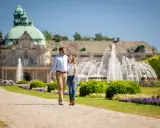 Ein Paar spaziert durch den Kurpark in Bad Oeynhausen. Hier kann man die schönen Brunnen und die Architektur genießen.