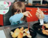 Kind mit blauer Kleidung weint, während es isst. Ein Teller mit Kartoffeln und Fleisch. Hilfe bei picky eater syndrom.