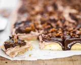 En chokladkaka i långpanna med fluffig chokladkräm och glansig chokladglasyr, toppad med krossad choklad och bitar av godis.