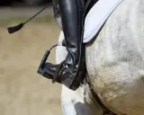 Jeździec w czarnym bucie z ostrogami na koniu.