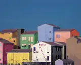 Case colorate e un cielo blu intenso, un paesaggio che ricorda le opere di Franco Fontana.