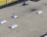 Flachdach mit Kiesbelag und mehreren Lichtkuppeln. Die harte Bedachung bietet Brandschutz und schützt vor Witterungseinflüssen.